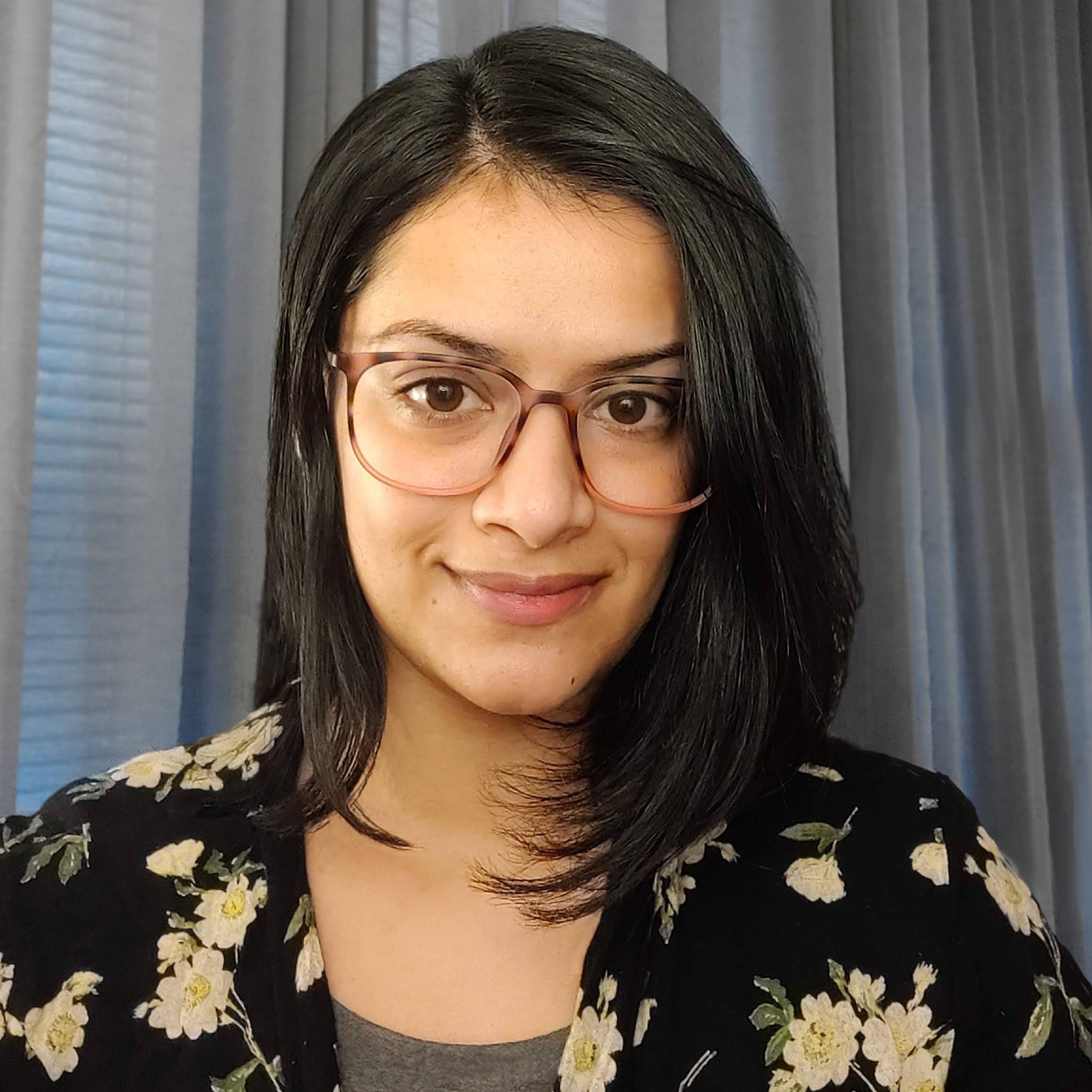 Pooja smiling, wearing glasses