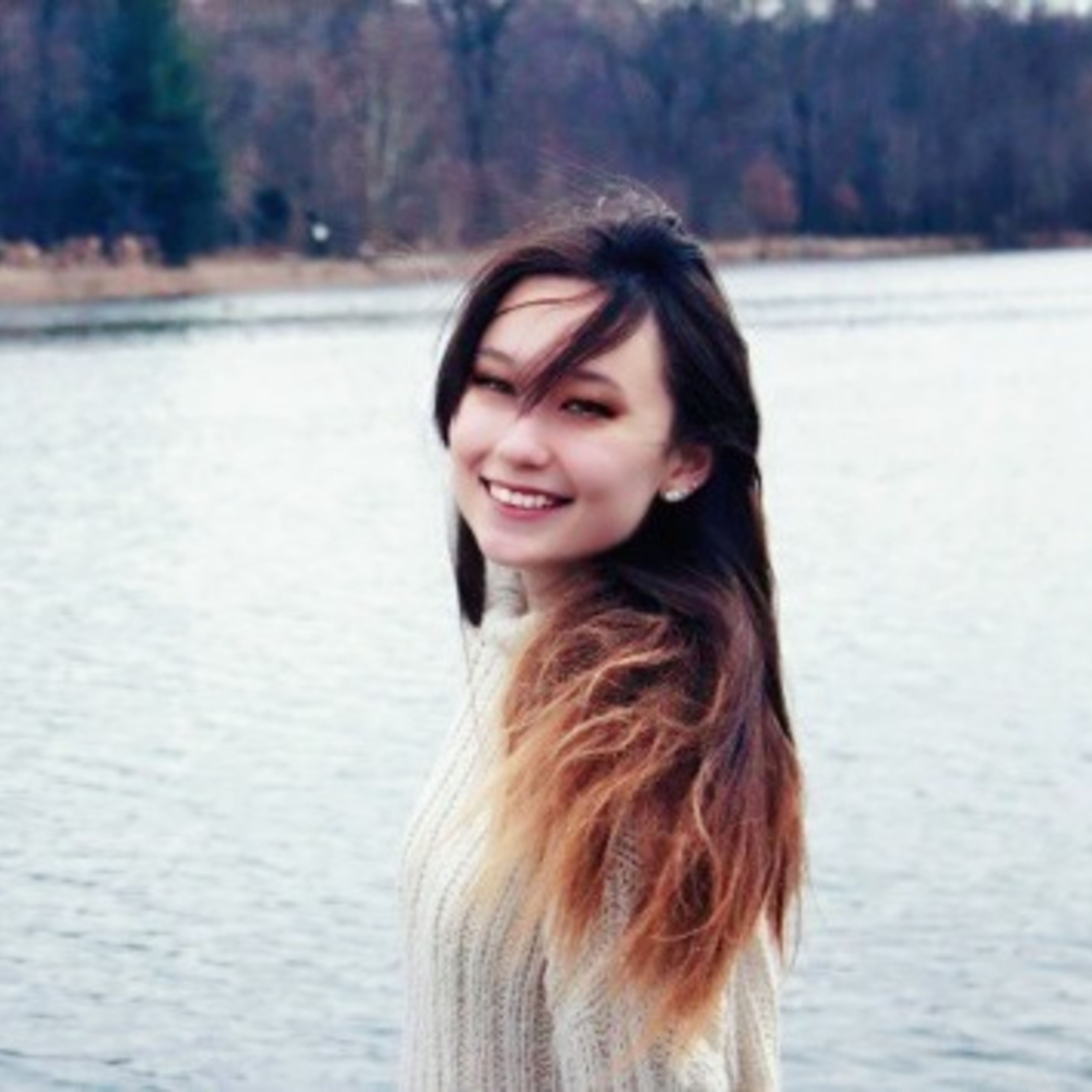Amelia smiling, turned to the side in front of a lake
